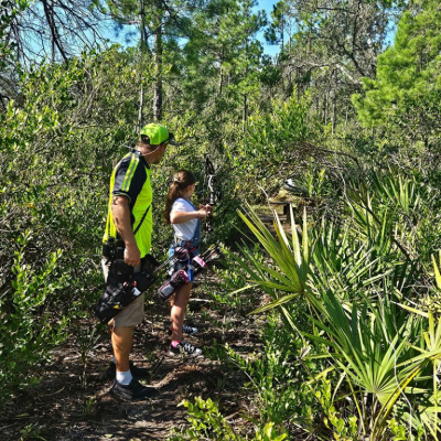 Man and girl in woods with bows
